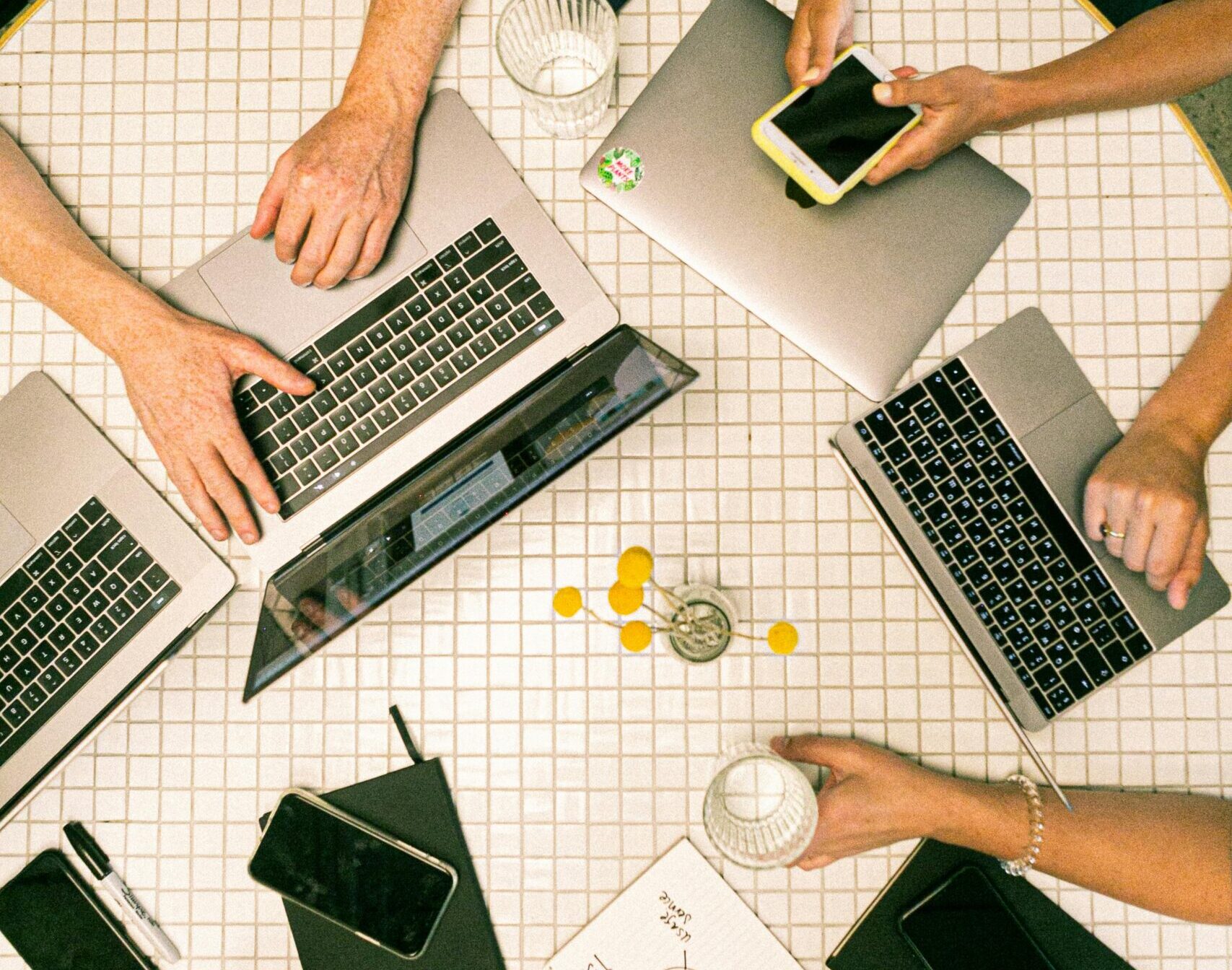 Home Top view of a team collaborating with laptops, phones, and notes in a modern office.